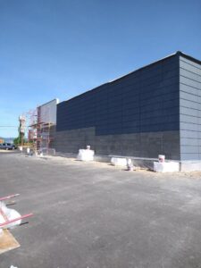 Commercial building with dark grey stucco or panel siding and scaffolding by Eastern Stucco Restorations in Rock Hill, SC.