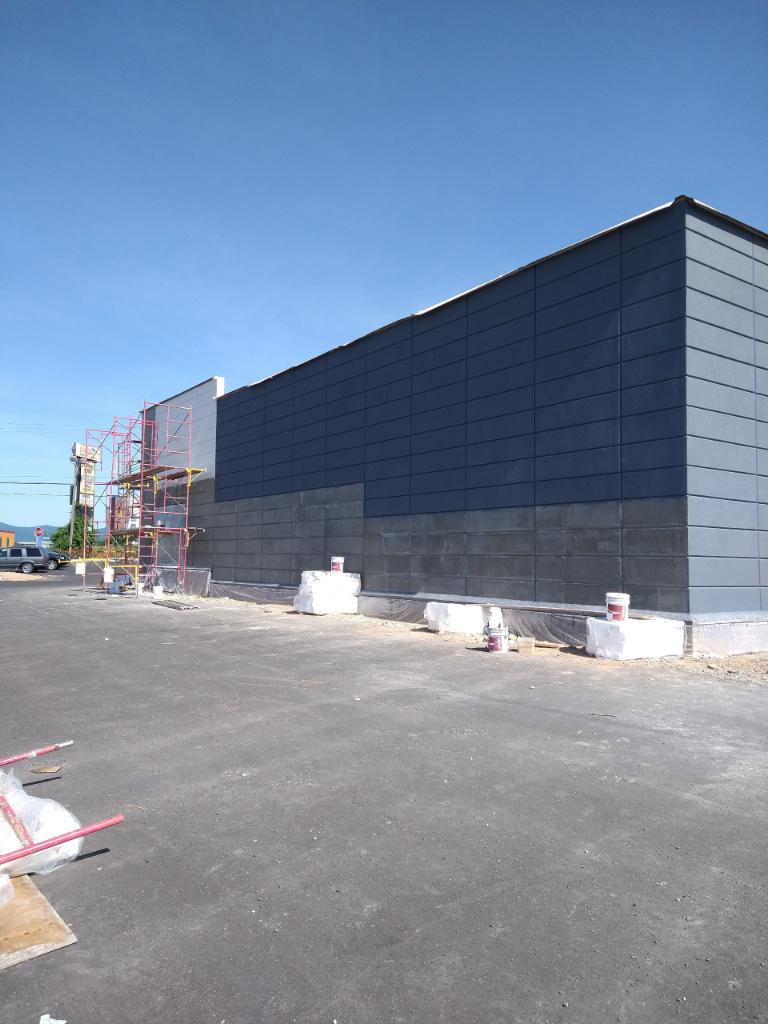 Commercial building with dark grey stucco or panel siding and scaffolding by Eastern Stucco Restorations in Rock Hill, SC.