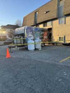 Large yellow drying ducts from Clean Care of New England trailer into a commercial building for water damage in Cranston, RI