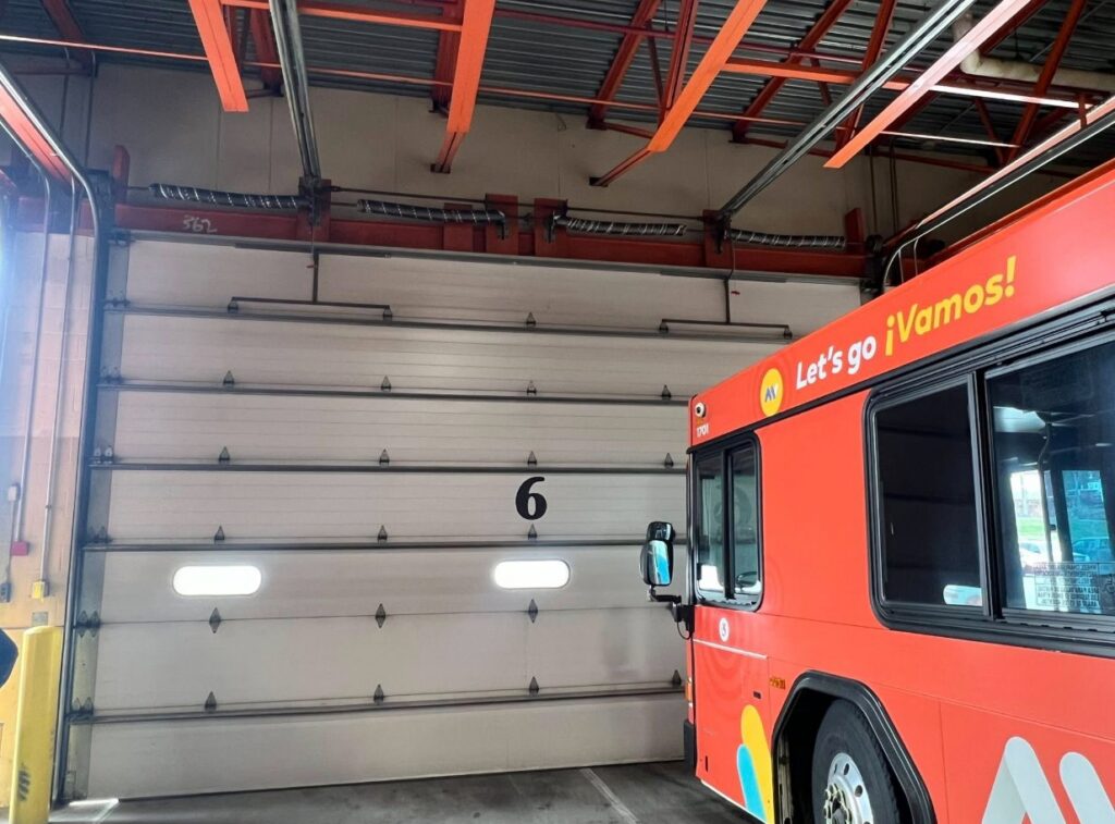 A large commercial garage door inside a bus depot, installed by NDI Garage Door in Plaistow, NH.