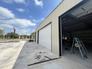 A white commercial garage door installed in a large building, indicating a job by RidgeLine Overhead Garage Door of CT in Danbury, CT