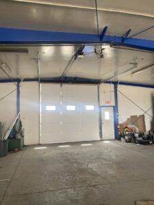 An interior view of a large white commercial garage door with windows and an opener installed by Apex Garage Doors in Columbus, OH.