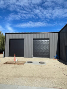 Two newly installed black commercial garage doors on a metal building, completed by ProLift Garage Doors of Canyon County in Nampa, ID.