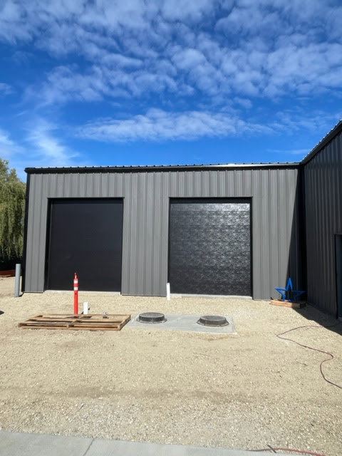 Two newly installed black commercial garage doors on a metal building, completed by ProLift Garage Doors of Canyon County in Nampa, ID.