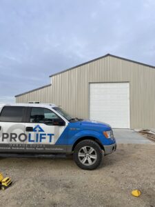 A ProLift Garage Doors of Canyon County truck parked in front of a commercial building with a newly installed garage door in Nampa, ID.