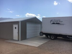 A commercial metal building with a newly installed garage door, with a branded Garage Door Mesquite truck parked nearby in Mesquite, NV.