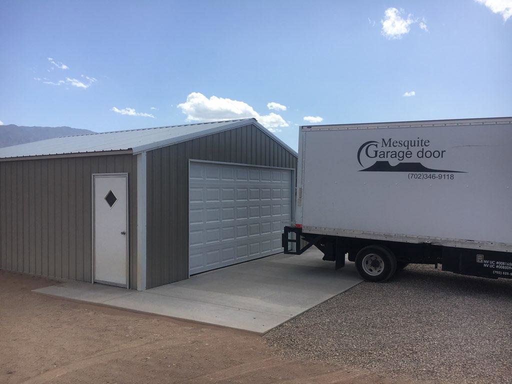 A commercial metal building with a newly installed garage door, with a branded Garage Door Mesquite truck parked nearby in Mesquite, NV.