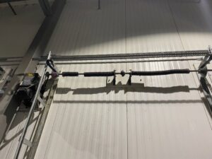 Interior view of a commercial garage door with torsion spring and chain drive, showing components serviced by Right Choice Doors in Layton, UT.