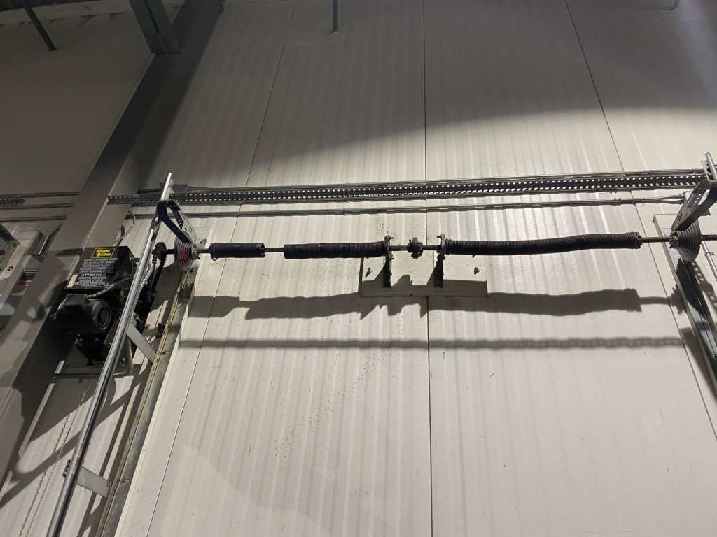 Interior view of a commercial garage door with torsion spring and chain drive, showing components serviced by Right Choice Doors in Layton, UT.
