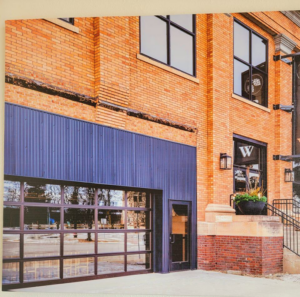 A large commercial glass garage door on a brick building, installed by Quality Garage Door in West Fargo, ND