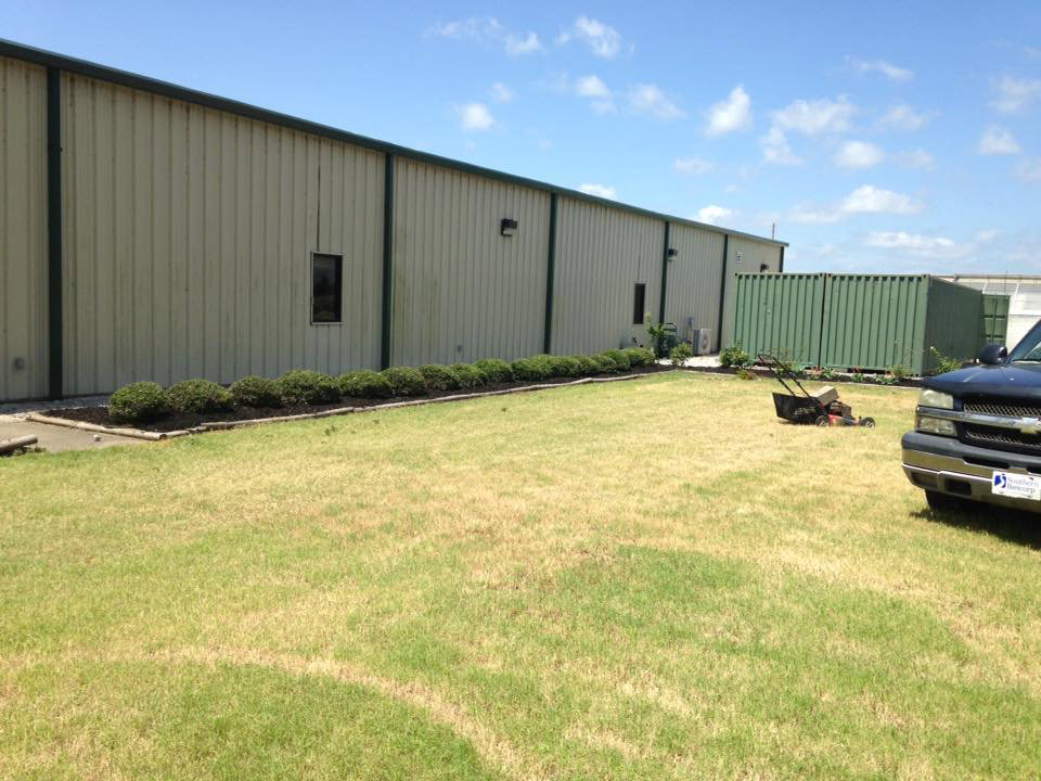A commercial property's lawn being maintained with a push mower, demonstrating services by Pro Green, LLC in Greenville, MS.