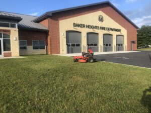 A red riding lawn mower parked on a freshly mowed lawn in front of the Baker Heights Fire Department, serviced by Neace's Lawn Care LLC in Martinsburg, WV.