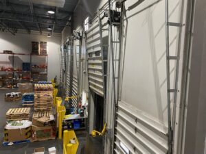 Multiple commercial loading dock garage doors in a warehouse setting, indicating commercial service by Right Choice Doors in Layton, UT.