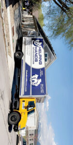A Helping Hands Moving & Maids truck with its back open, loading items on a pallet for a commercial move in Salt Lake City, UT.