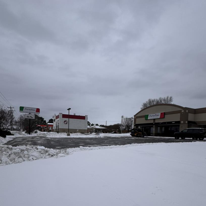 A commercial parking lot cleared of snow with a large pile of snow pushed aside by AMK Forestry in Conway, AR.