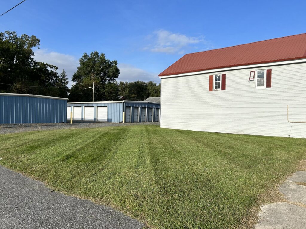 A commercial property featuring a neatly striped lawn next to storage units, maintained by A & J Lawn Care LLC in Corsicana, TX.