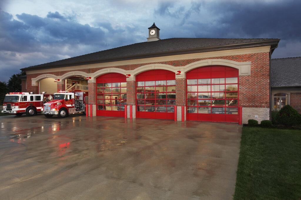 Commercial red full-view glass garage doors installed on a fire station by Elite Door in Winchester, CA.
