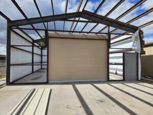 A beige commercial roll-up door installed on a metal-framed building under construction by Precision Garage Door of Albuquerque and Santa Fe, NM.