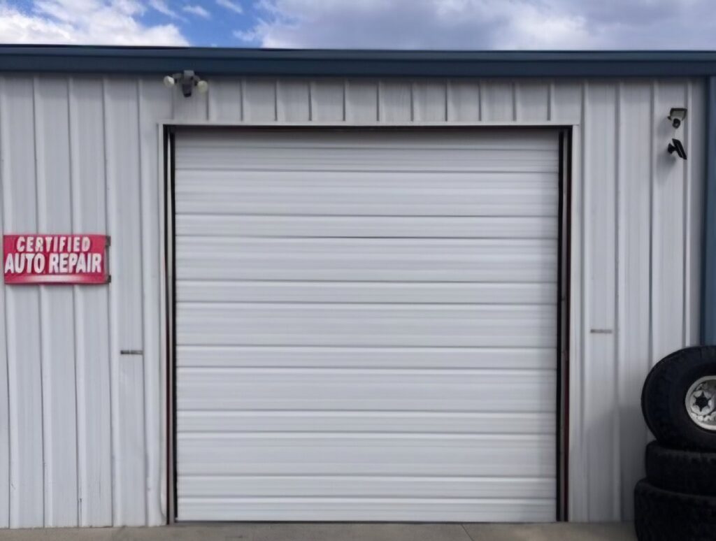 A white commercial roll-up garage door installed on a building by 775 Overhead Doors in Carson City, NV.