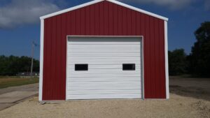 Commercial white roll-up garage door installed on a red building by Cedar Valley Garage Doors in Waterloo, IA