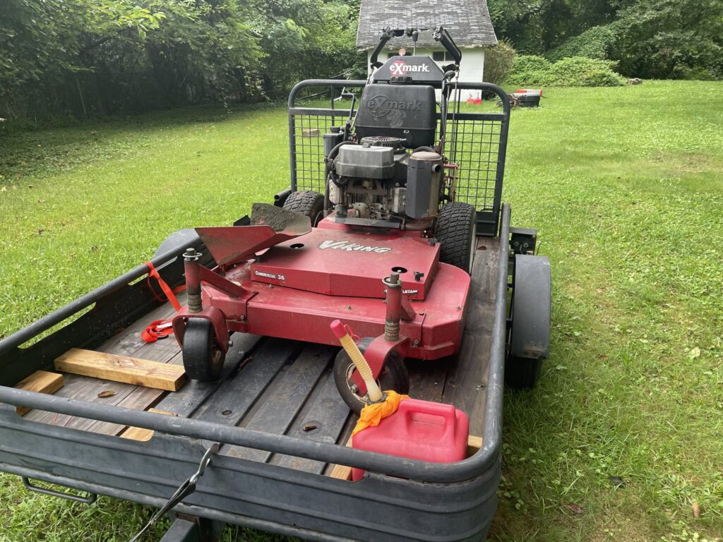 A commercial stand-on lawn mower on a trailer, essential equipment for Mike's Lawn Care Service in Dover, DE.