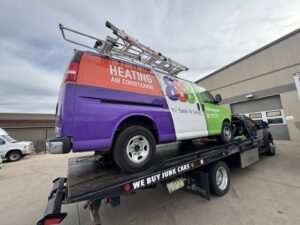 A commercial heating and air conditioning van being towed on a flatbed truck by Black Mamba Towing & Recovery Llc in Aurora, CO.