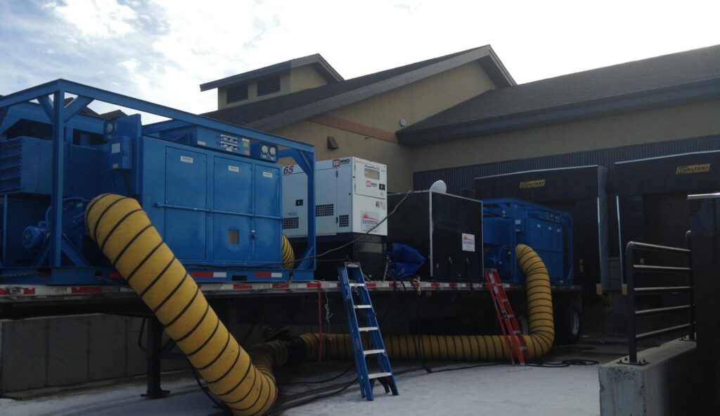 Commercial water damage drying equipment with yellow ducts leading into a building by Dayspring Restoration in Butte, MT