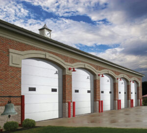 Commercial white garage doors with windows installed on a brick fire station building by Elite Door in Winchester, CA.
