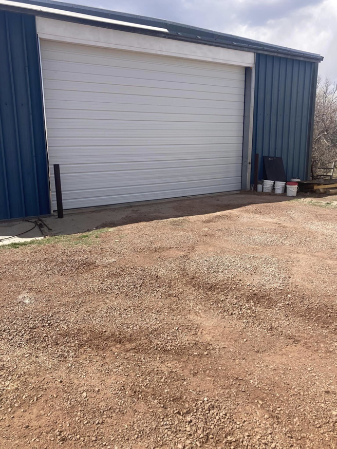 A commercial white sectional garage door on a blue metal building, installed by Doors & more,inc in Quincy, IL