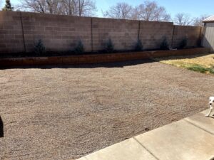 A completed gravel landscaping project with a retaining wall by Green Thumb Lawn Care & Maintenance, LLC in Rio Rancho, NM.
