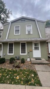 A residential house with newly installed green siding and white trim, completed by DJ Paz All Siding & Roofing Construction in Iowa City, IA