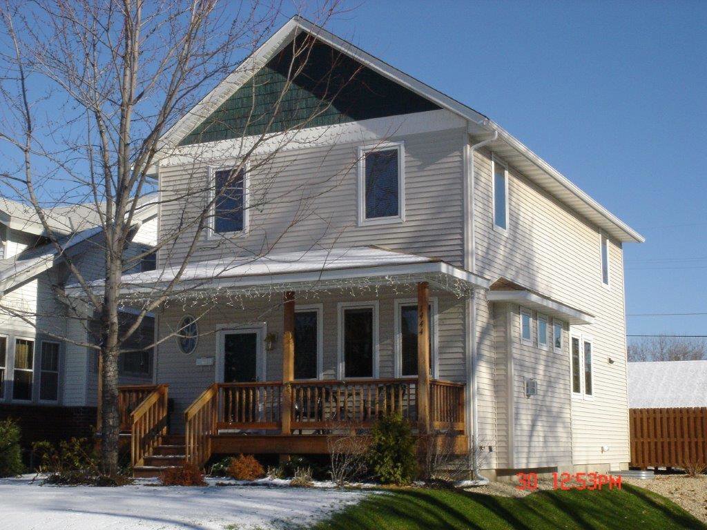 Newly installed light beige siding and a new wooden porch on a house by Capital Siding, Windows & Roofing, Woodbury, MN.