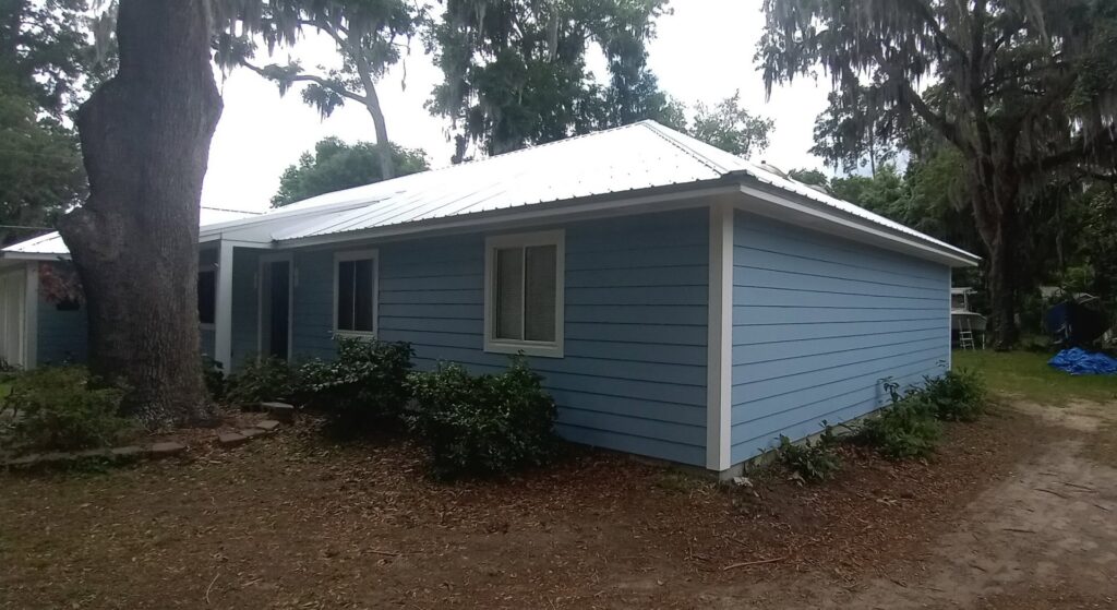 A house with newly completed light blue siding and a white metal roof by Action Roofing and Siding Co in South Saint Paul, MN
