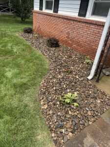 A beautifully completed curved garden bed filled with river stones and small plants, maintained by Neace's Lawn Care LLC in Martinsburg, WV.