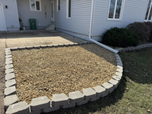 Completed rock bed landscaping with retaining wall in front of a house by Elite Property Care in Albany, NY.