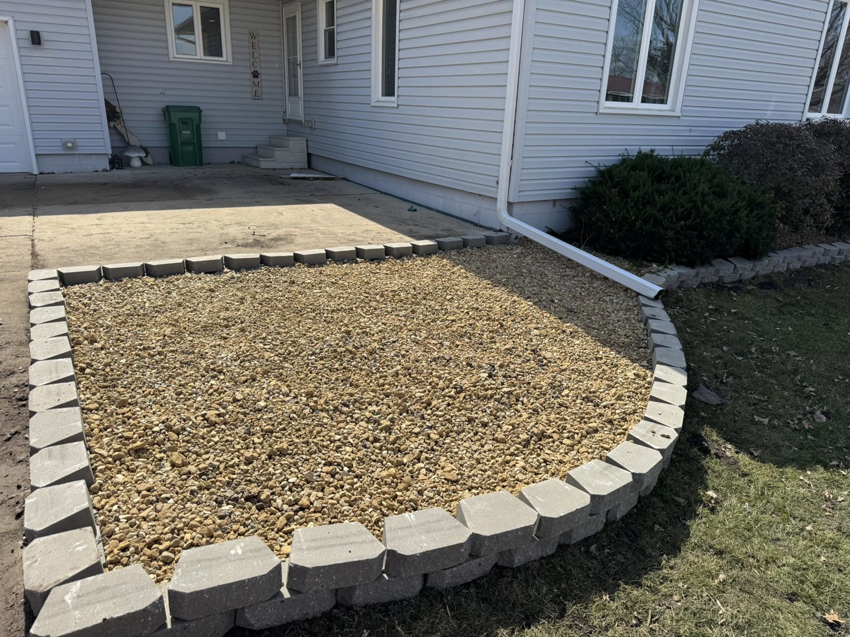 Completed rock bed landscaping with retaining wall in front of a house by Elite Property Care in Albany, NY.