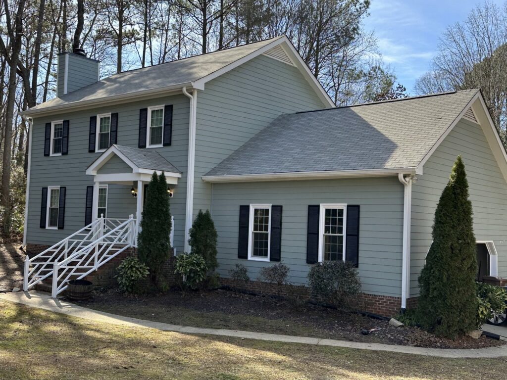 A newly sided residential house with light green siding and dark shutters, a completed project by ING Contractors LLC in Cary, NC.
