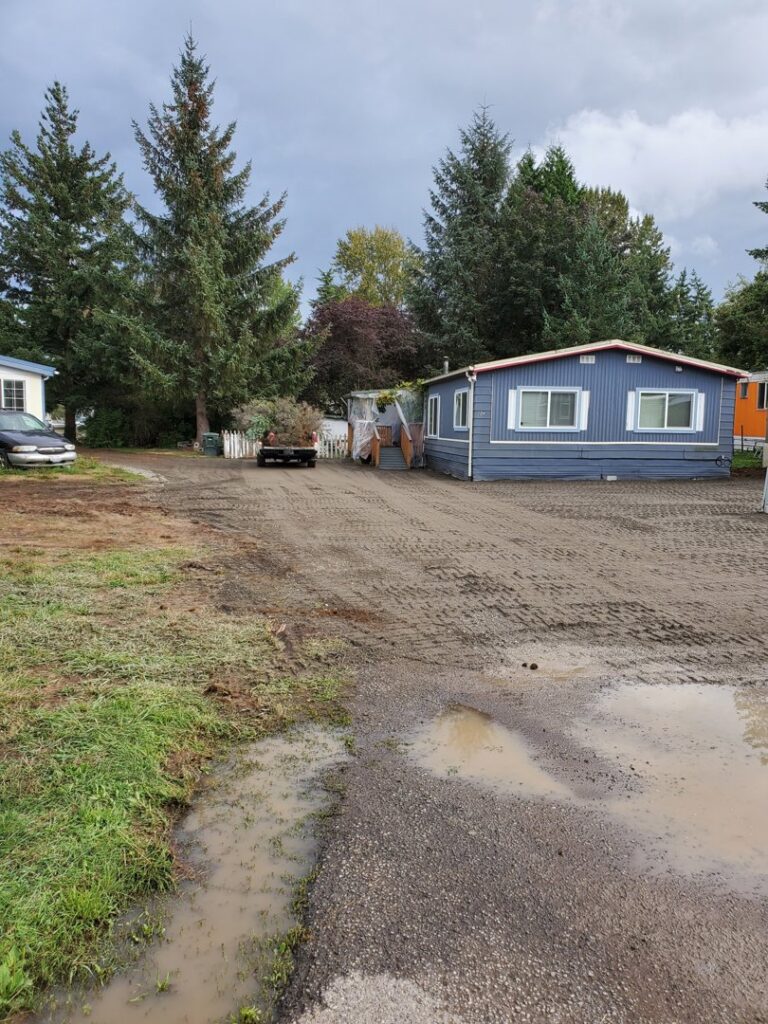A recently cleared and graded area with puddles, showing completed site preparation by ROUGH 2 READY in Auburn, AL