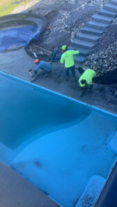 Workers installing concrete decking around a new swimming pool by Backyard Escapes by Kerner Pools & Spas in Bismarck, ND.
