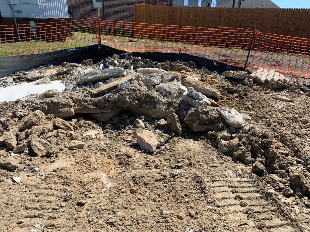A pile of concrete and dirt demolition debris on a construction site with safety fencing by Vaquero Demolition in Lewisville, TX.