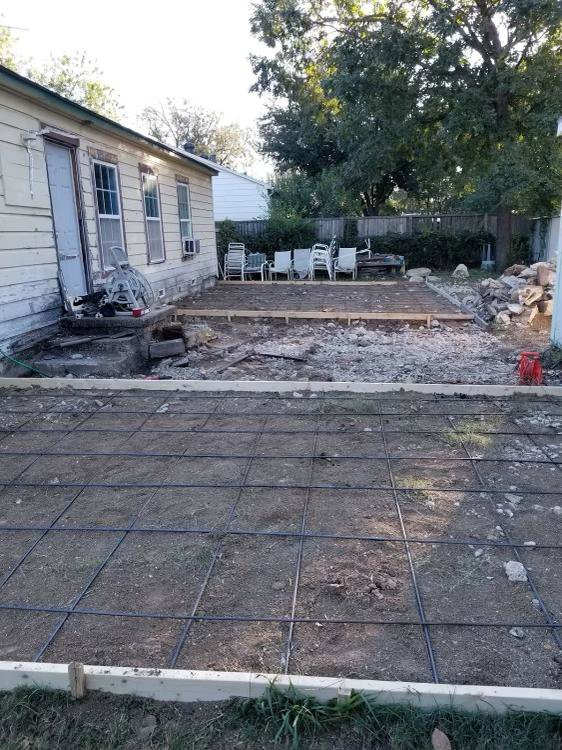 A backyard showing rebar for new concrete installation with demolition rubble in the background by Vaquero Demolition in Lewisville, TX.