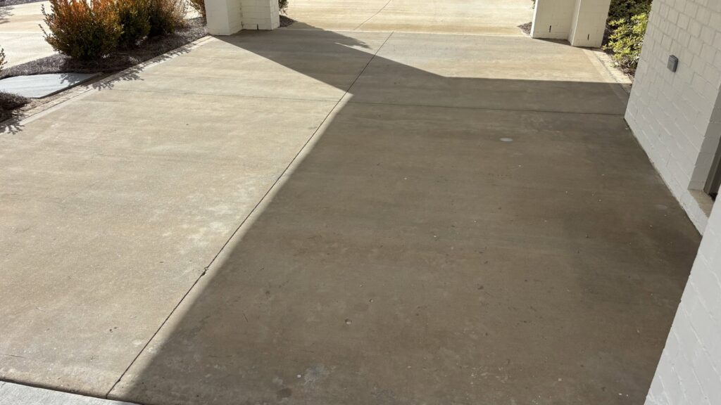 Concrete driveway cleaning in progress, showing a clear clean line by Plains Power Washing in Auburn, AL.