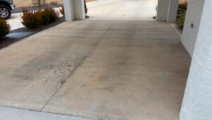 A concrete driveway showing a clear line where half has been cleaned by Plains Power Washing in Auburn, AL.