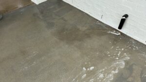 A concrete surface covered with soap and water during a cleaning service by Plains Power Washing in Auburn, AL.