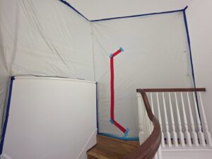 A containment barrier set up around a staircase for water damage remediation by Risk Free Serv Water Damage Repair San Diego, CA