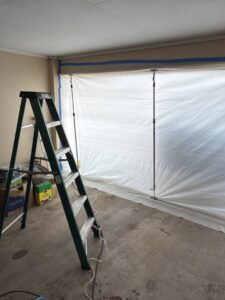 A ladder and plastic sheeting containment setup for water damage remediation by Restoration Xperts Emergency 24/7 in Deerfield Beach, FL.