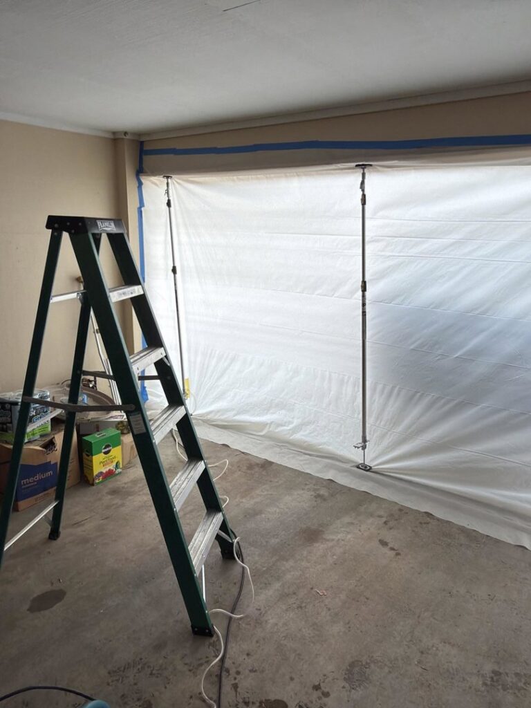 A ladder and plastic sheeting containment setup for water damage remediation by Restoration Xperts Emergency 24/7 in Deerfield Beach, FL.