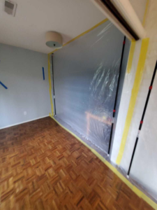 A room with plastic sheeting and tape set up for containment during water damage restoration by PacWest Restoration in Tigard, OR.