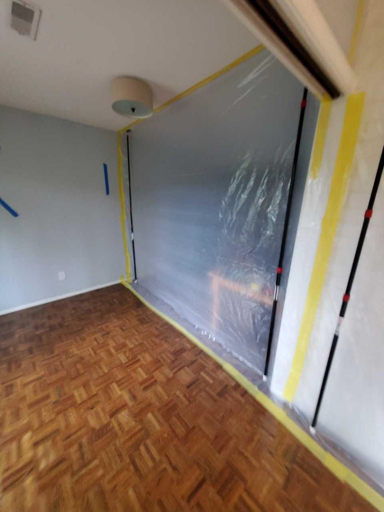 A room with plastic sheeting and tape set up for containment during water damage restoration by PacWest Restoration in Tigard, OR.