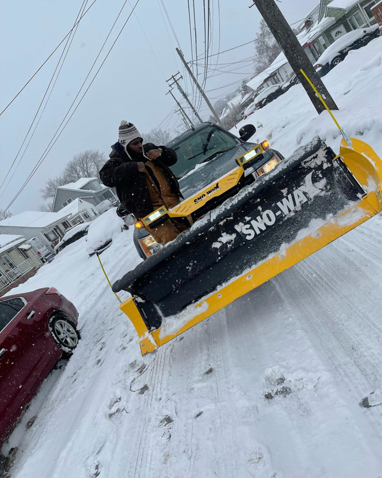 A contractor standing next to a truck equipped with a Sno-Way snow plow on a snowy street for PJs Full Service Contractors in Cleveland, OH.